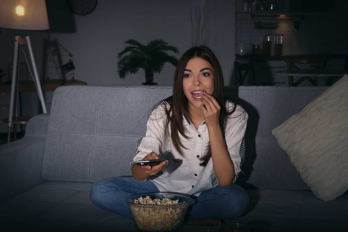 ragazza guarda le serie tv seduta sul divano